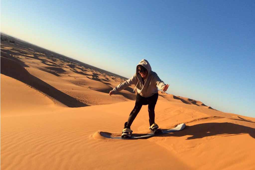 Traveler walking across the Erg Chebbi dunes at sunrise in Merzouga